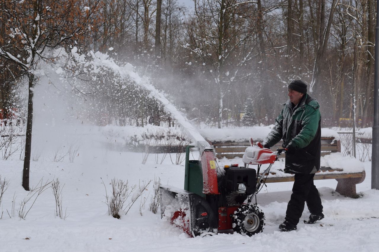 portfolio-03 A man uses a snow blower in a snowy park during wintertime.