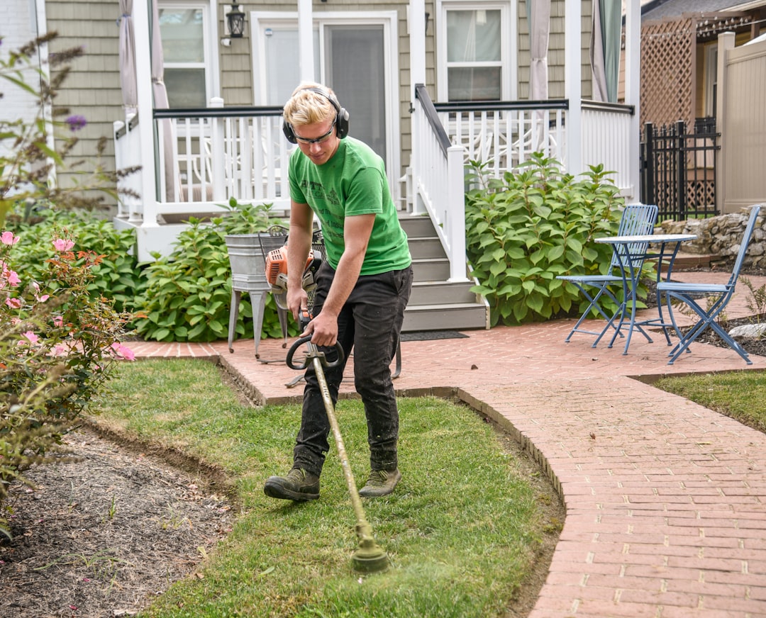 portfolio-01 Man weed wacking a customers grass next to a sidewalk with the house in the background.