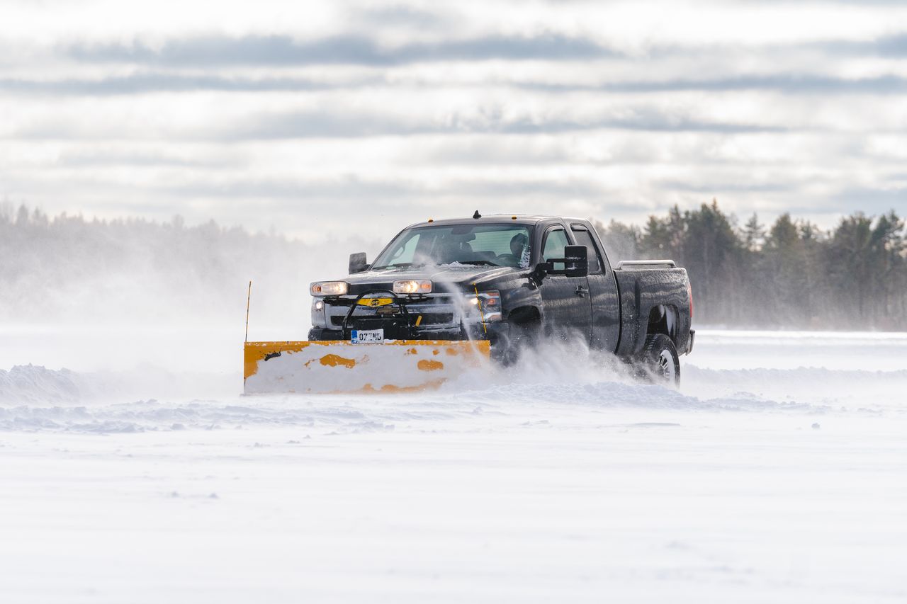 portfolio-06 A powerful truck with a snowplow clearing a snowy road in winter.